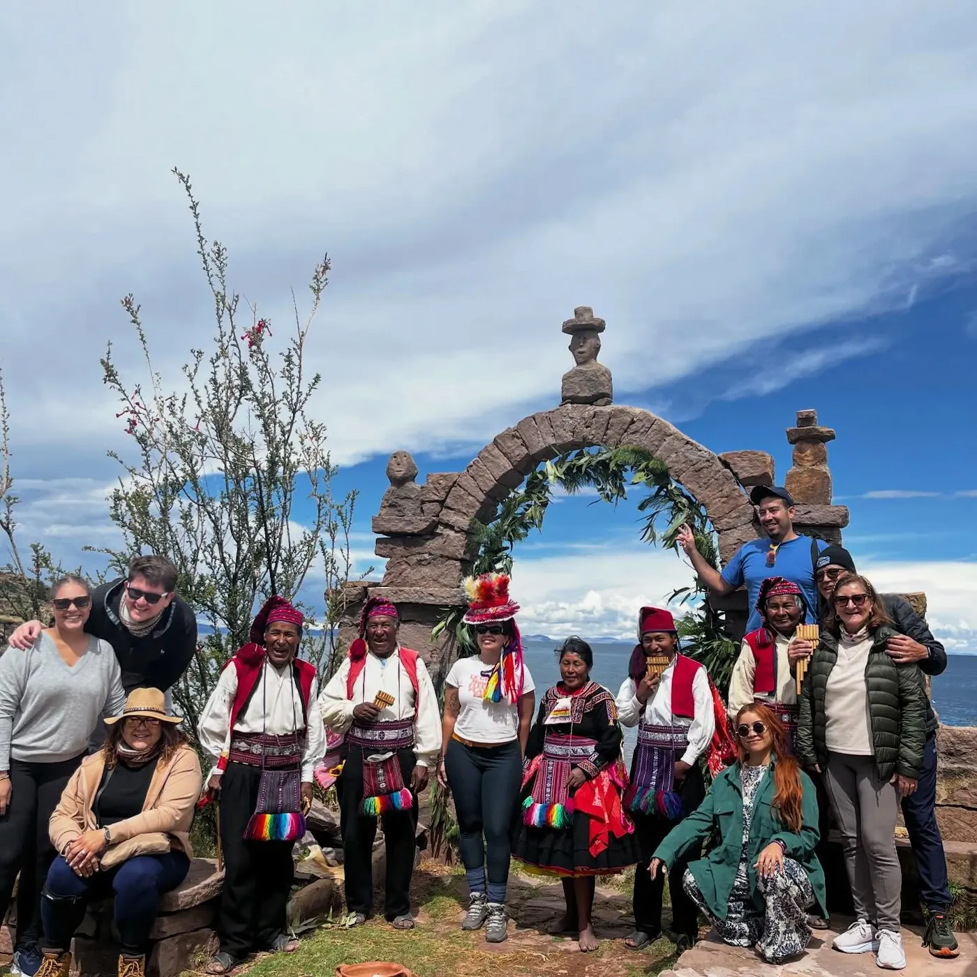Viajeros con pobladores bajo un arco de piedra a orillas del Lago Titicaca